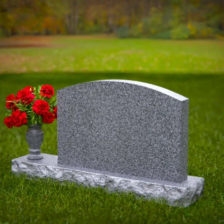 Waved granite headstones featuring floral vase tribute.