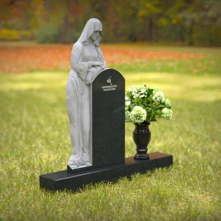 Praying angel sculpture resting beside floral tribute on classic headstones.