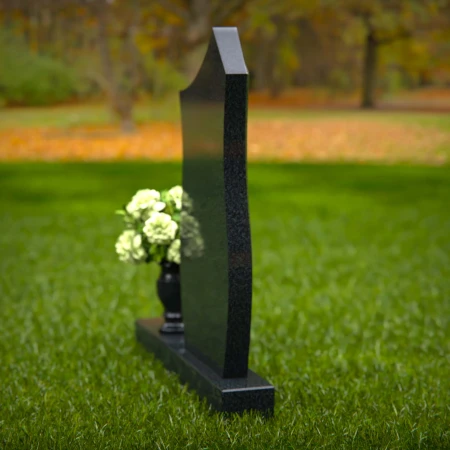 Modern contoured granite headstones with single flower vase.
