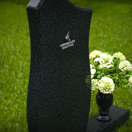 Modern contoured granite headstones with single flower vase.