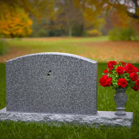 Waved granite headstones featuring floral vase tribute.