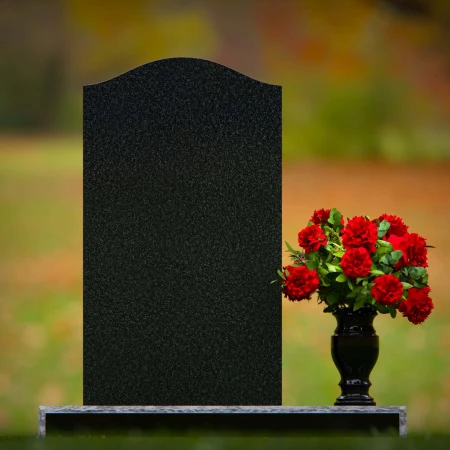 Classic granite headstones with arched top and flower vase.