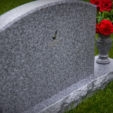 Waved granite headstones featuring floral vase tribute.