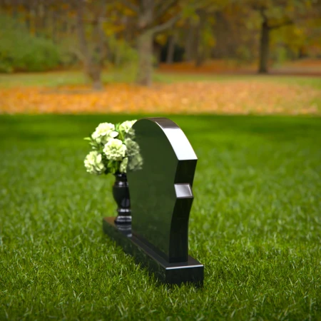 Unique headstones featuring artistic arch designs and floral vases.