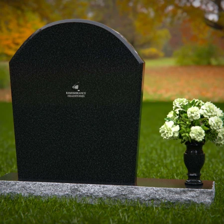 Arched granite headstones with elegant form and flower vase.