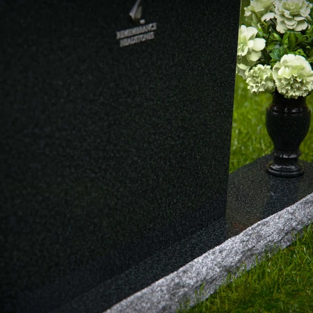 Arched granite headstones with elegant form and flower vase.