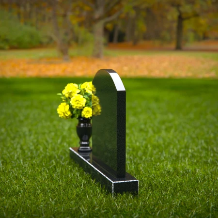 Classic arched granite headstones with polished vase tribute.