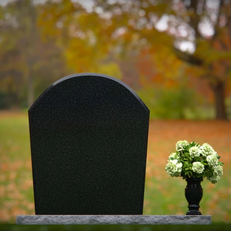 Arched granite headstones with elegant form and flower vase.