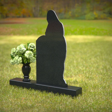 Praying angel sculpture resting beside floral tribute on classic headstones.