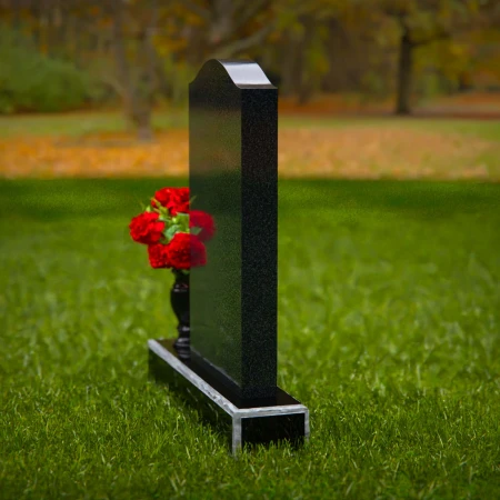 Classic granite headstones with arched top and flower vase.