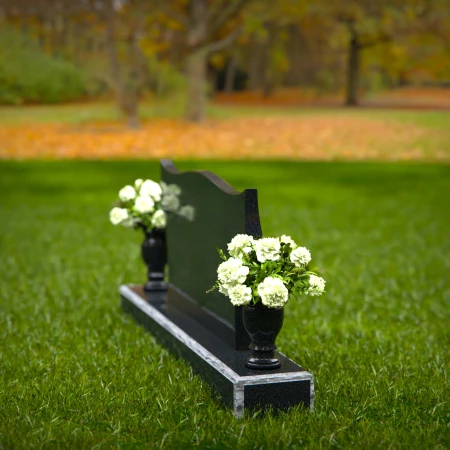 Elegant headstones with sculpted wave design and dual floral vases.
