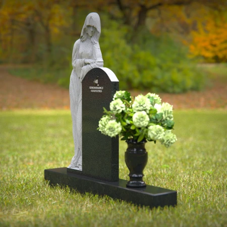 Praying angel sculpture resting beside floral tribute on classic headstones.