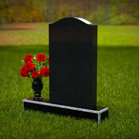Classic granite headstones with arched top and flower vase.