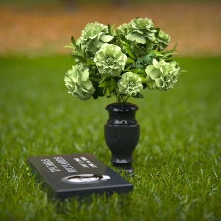 Compact headstones featuring photo inlays and floral vases for memorials.