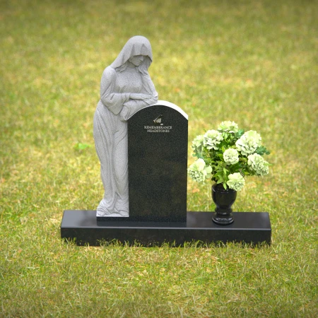 Praying angel sculpture resting beside floral tribute on classic headstones.