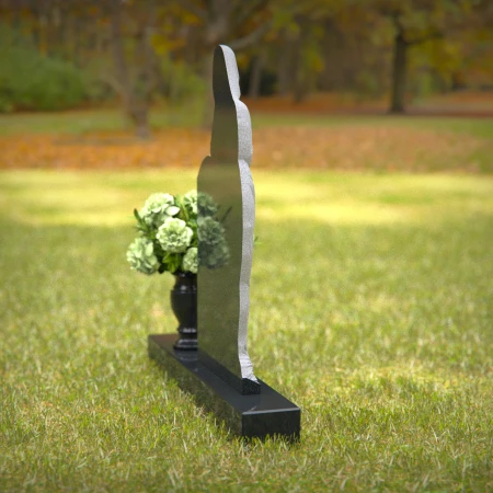 Praying angel sculpture resting beside floral tribute on classic headstones.